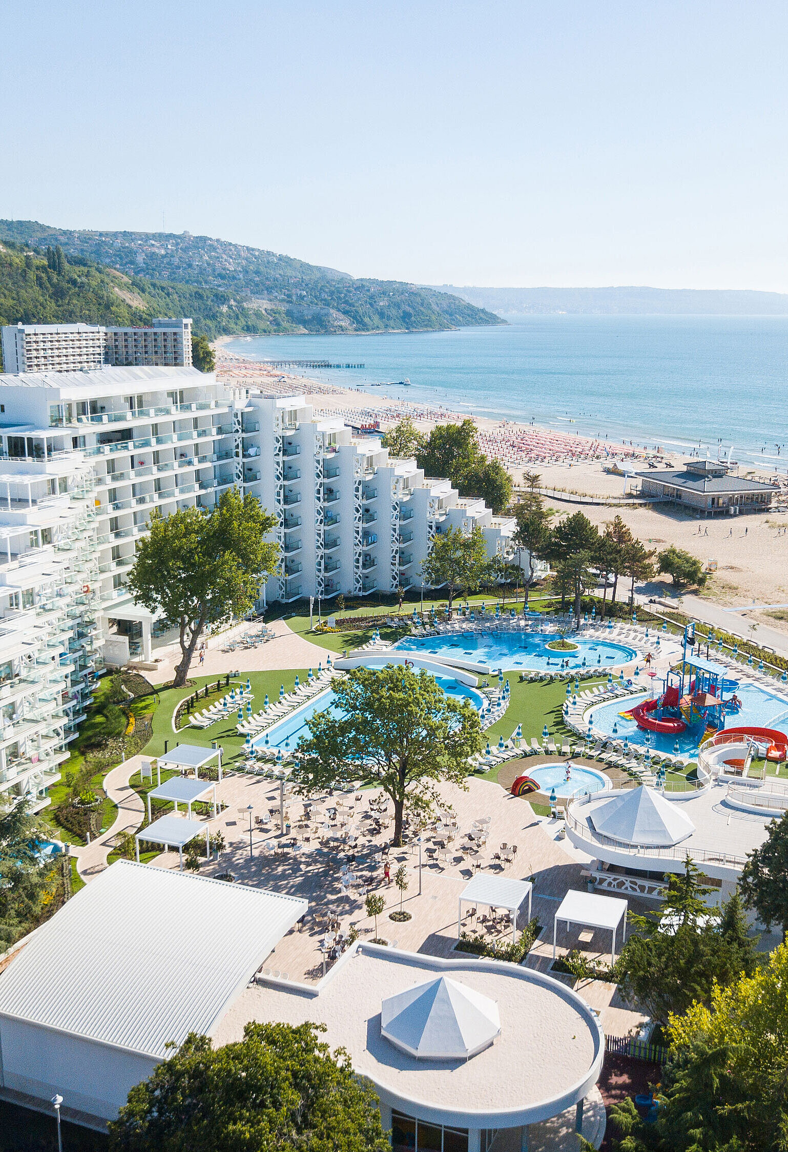 Außenansicht Luftaufnahme des Resorts mit Pools, Strand, modernem Hotelgebäude und Blick auf das Meer und die Küste